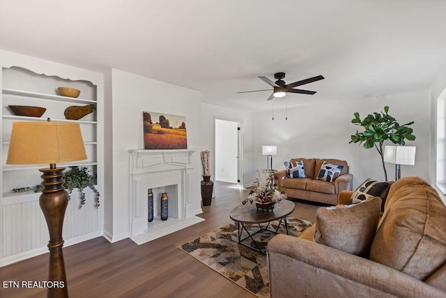 living room featuring a fireplace with flush hearth, wood finished floors, and a ceiling fan