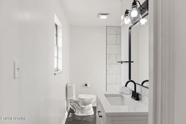 bathroom featuring toilet, vanity, and baseboards