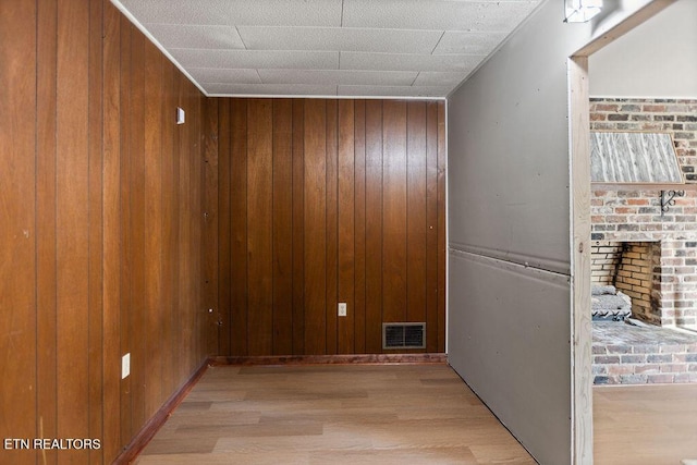 hallway featuring visible vents, wood finished floors, and wood walls