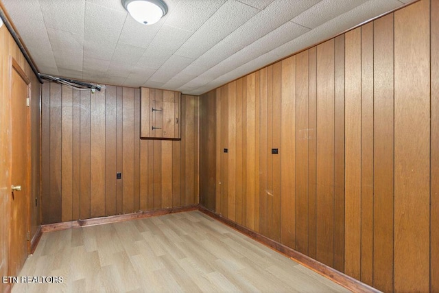 empty room with wood walls and light wood-type flooring