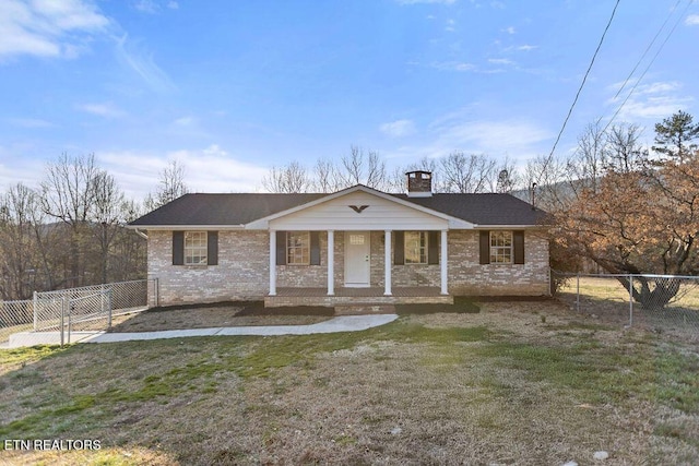 view of front of house featuring brick siding, a front lawn, fence, and covered porch