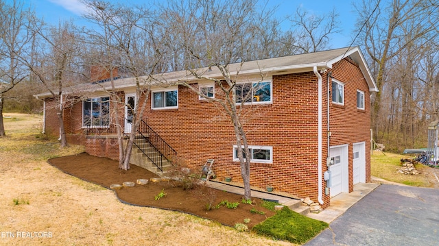 view of home's exterior featuring a garage, brick siding, and driveway