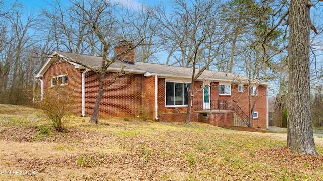 view of front of house with a front lawn, brick siding, and a chimney