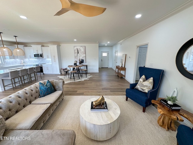 living area with recessed lighting, light wood-style floors, and ornamental molding