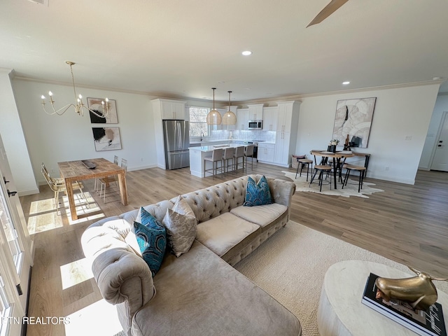 living room featuring light wood finished floors, a notable chandelier, and crown molding