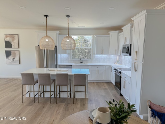 kitchen featuring a kitchen bar, a sink, tasteful backsplash, a kitchen island, and appliances with stainless steel finishes