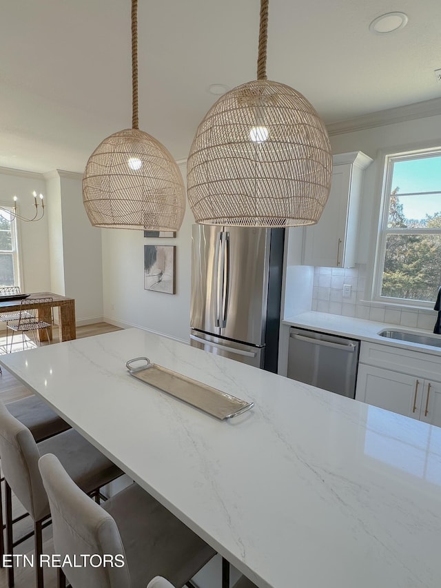 kitchen featuring a breakfast bar, a sink, white cabinetry, appliances with stainless steel finishes, and crown molding