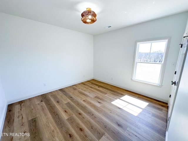 unfurnished room with light wood-style floors, visible vents, and baseboards