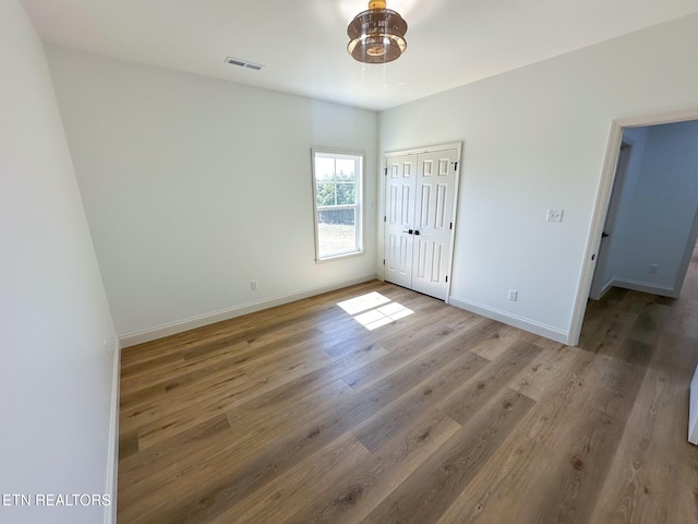 unfurnished bedroom featuring baseboards, visible vents, a closet, and light wood-type flooring