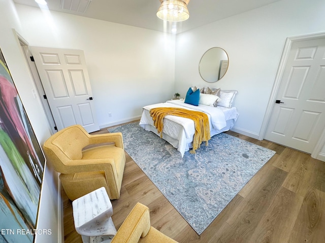 bedroom featuring visible vents, baseboards, and wood finished floors