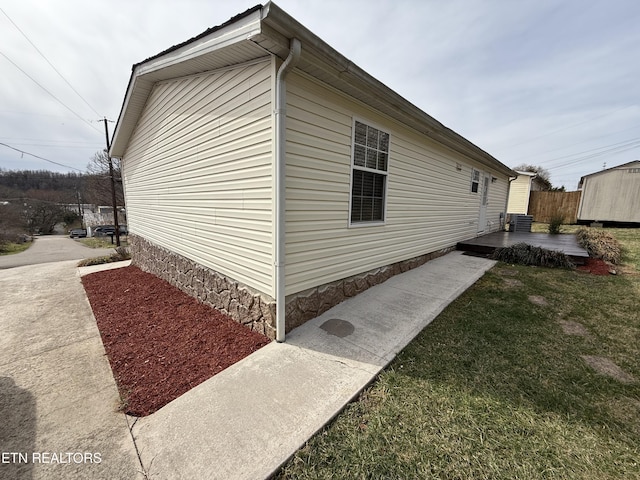 view of side of property with a patio, fence, a yard, an outdoor structure, and central air condition unit