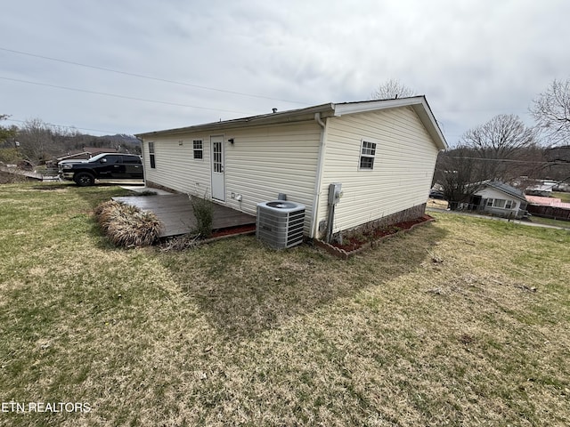 view of property exterior featuring a yard, central AC, and a wooden deck