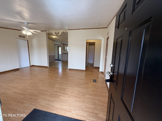 empty room with visible vents, light wood-style flooring, baseboards, and a ceiling fan