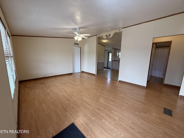 spare room with visible vents, a ceiling fan, light wood-style floors, crown molding, and baseboards