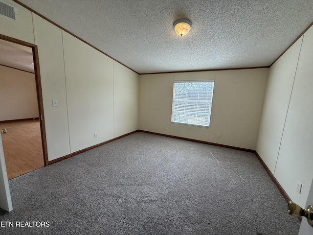 carpeted spare room featuring visible vents, a textured ceiling, and ornamental molding