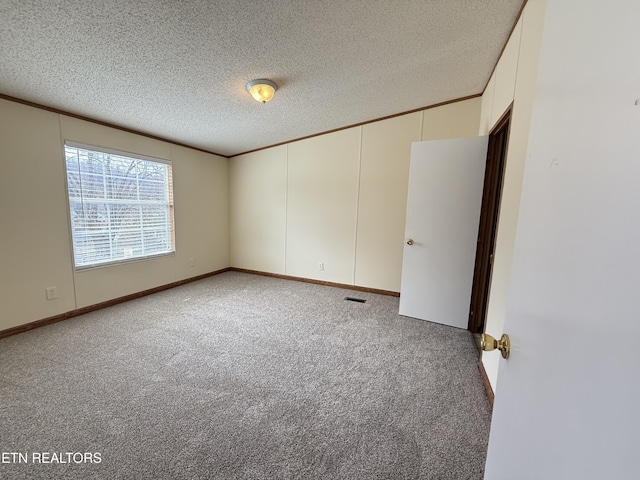 carpeted spare room with visible vents, a textured ceiling, and crown molding