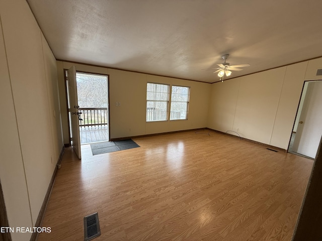 spare room with light wood-style floors, visible vents, a wealth of natural light, and ornamental molding