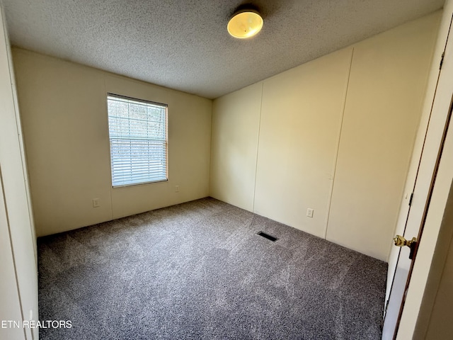 carpeted spare room featuring visible vents and a textured ceiling