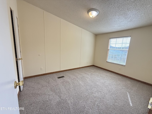 unfurnished room with baseboards, visible vents, carpet floors, and a textured ceiling