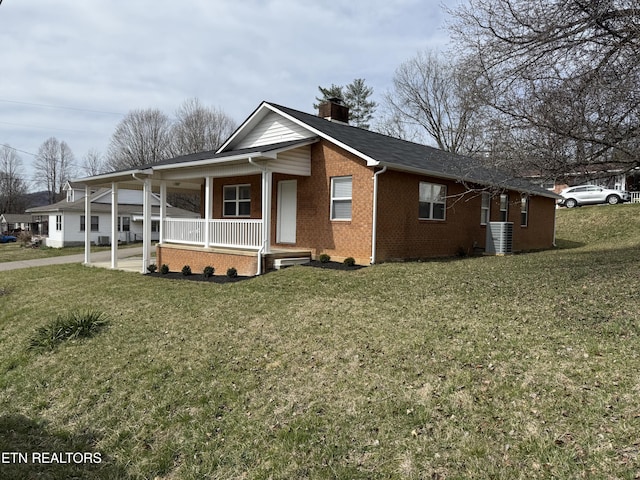 view of front of house featuring cooling unit, covered porch, a front yard, brick siding, and a chimney