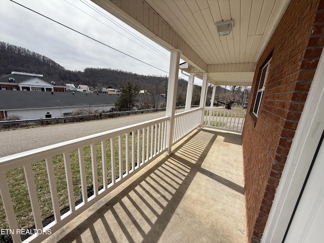 balcony featuring covered porch and a wooded view