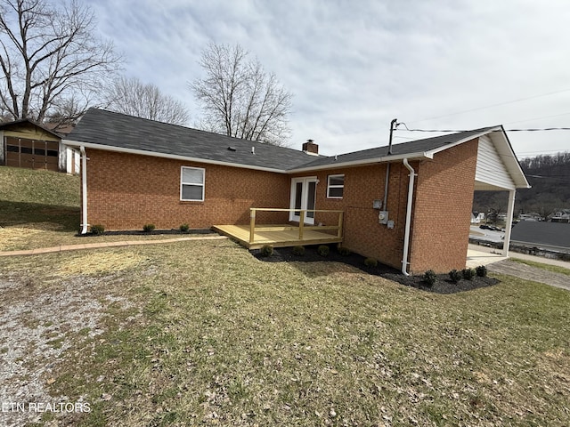 back of property featuring a deck, a lawn, brick siding, and a chimney