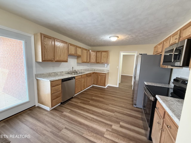 kitchen featuring dark wood-style floors, baseboards, a sink, stainless steel appliances, and a textured ceiling