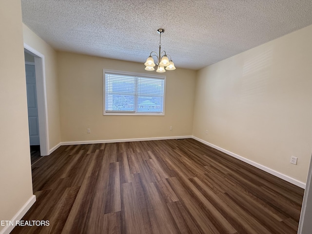 spare room featuring a notable chandelier, a textured ceiling, baseboards, and dark wood-style flooring