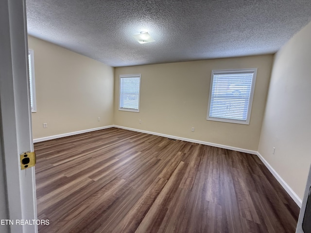 spare room with baseboards, a textured ceiling, and dark wood-style flooring