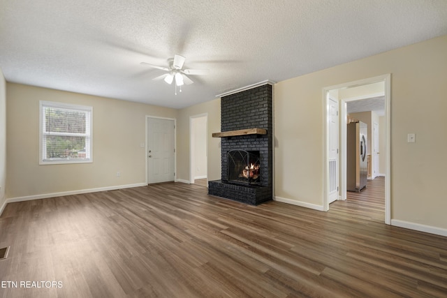 108 Burke St, Pennington Gap, VA 24277 - unfurnished living room with a textured ceiling, a ceiling fan, a brick fireplace, visible vents, and wood finished floors