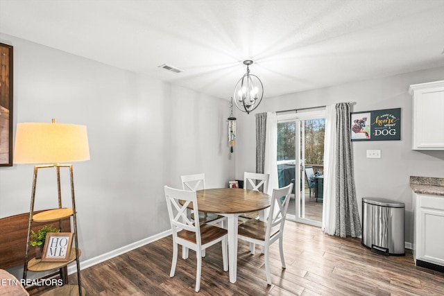 dining space featuring baseboards, wood finished floors, visible vents, and a chandelier