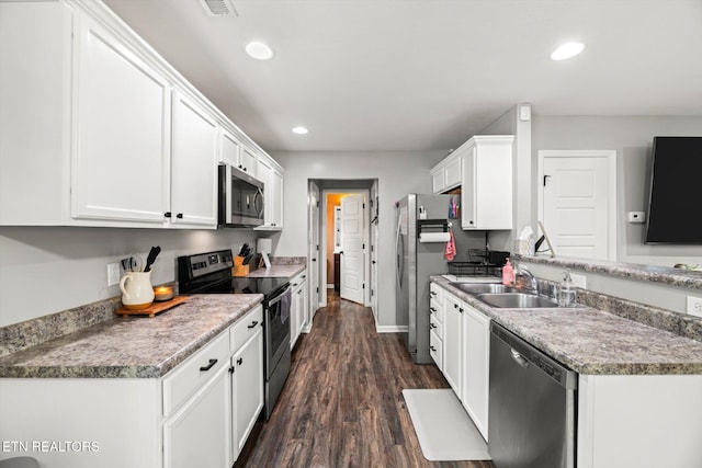 kitchen with a sink, stainless steel appliances, white cabinets, and recessed lighting