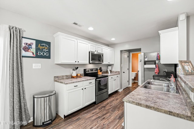 kitchen with visible vents, a sink, stainless steel appliances, white cabinetry, and dark wood-style flooring