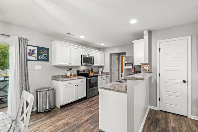 kitchen with visible vents, dark wood-type flooring, appliances with stainless steel finishes, a peninsula, and white cabinets