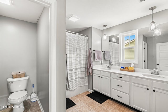 bathroom with double vanity, toilet, baseboards, and a sink