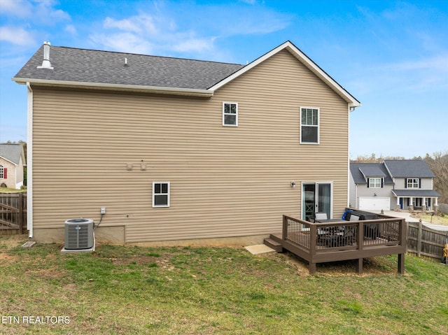 rear view of property featuring central air condition unit, fence, a lawn, and a wooden deck