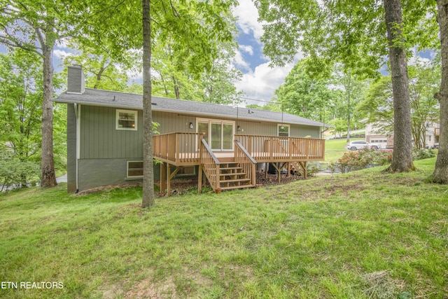 rear view of property featuring a chimney, stairway, a wooden deck, and a lawn