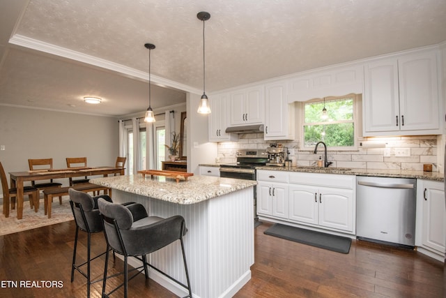 kitchen with a sink, stainless steel appliances, under cabinet range hood, dark wood-style flooring, and backsplash