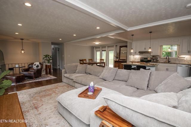 living room with a textured ceiling, wood finished floors, ornamental molding, and recessed lighting