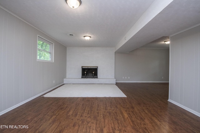 unfurnished living room with baseboards, a textured ceiling, a fireplace with raised hearth, and wood finished floors