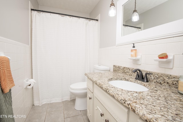 full bathroom featuring toilet, tile patterned flooring, tile walls, and a wainscoted wall