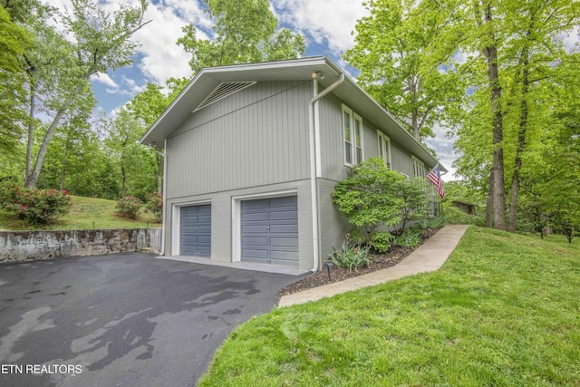 view of side of property with a yard, a garage, and aphalt driveway
