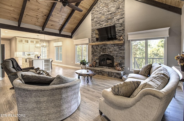 living area featuring baseboards, beamed ceiling, wood ceiling, light wood-style flooring, and a fireplace