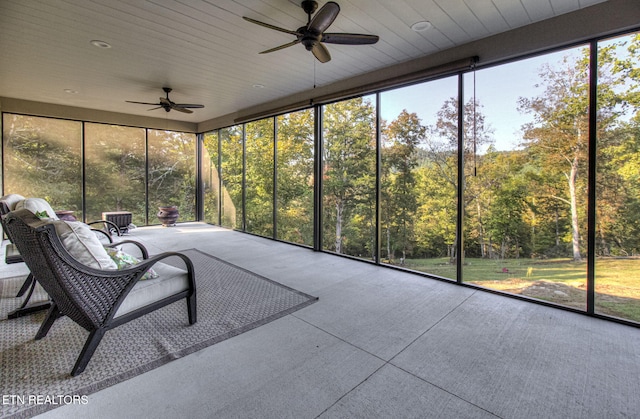 unfurnished sunroom featuring a forest view and ceiling fan