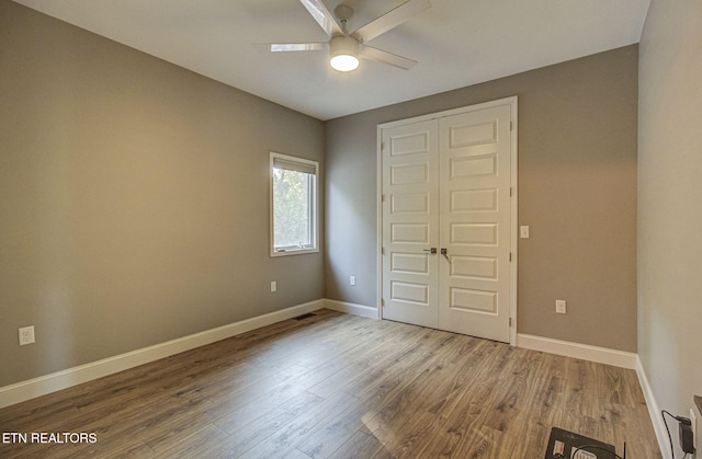 unfurnished bedroom with ceiling fan, visible vents, baseboards, and wood finished floors