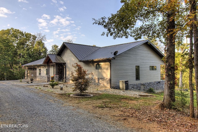 view of side of home featuring stone siding and metal roof