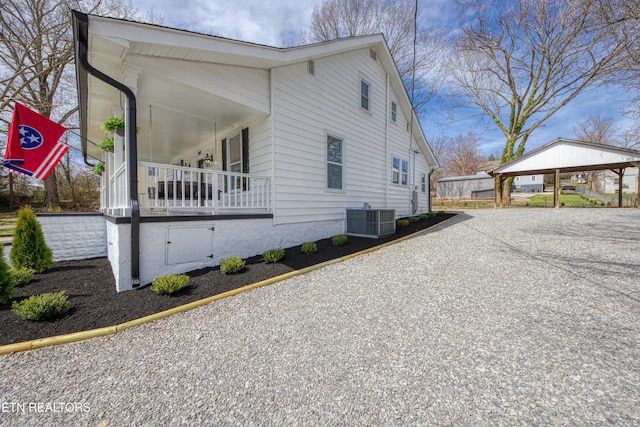 view of side of property with a carport, central AC unit, and gravel driveway