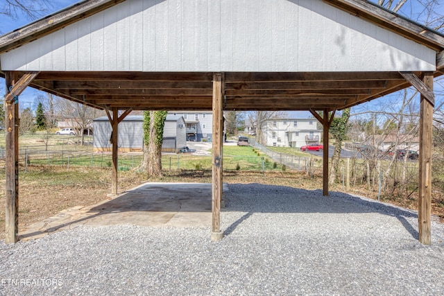 view of patio / terrace with gravel driveway, a carport, and fence