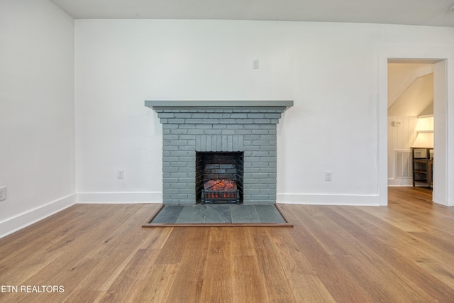 unfurnished living room featuring visible vents, baseboards, wood finished floors, and a fireplace