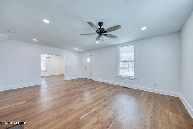 spare room with light wood finished floors, plenty of natural light, and visible vents